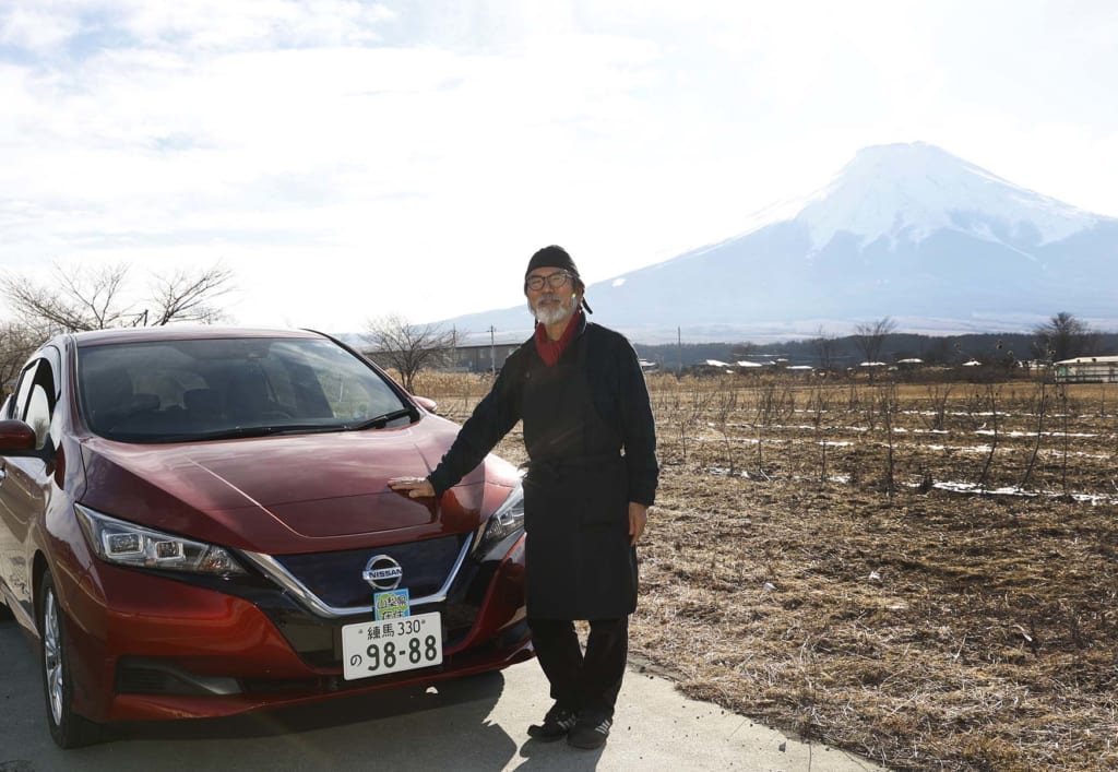 富士山の見える絶景スポットに停めた愛車リーフの前に立つ桑原さん