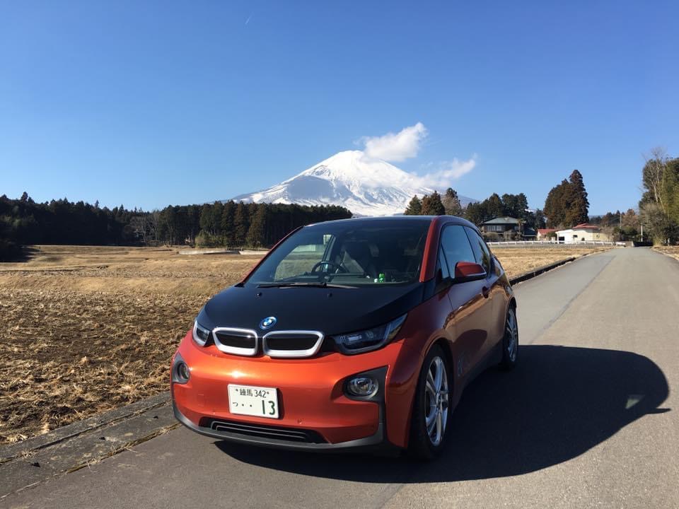 写真：快晴の富士山を背景に停車しているオレンジ＆黒ツートンのBMWi3