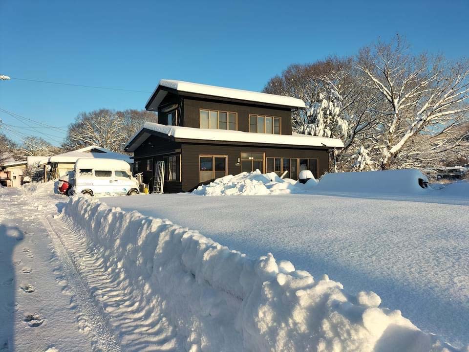 写真：畑や、建物や車の屋根の上に厚く雪が積もり一面雪景色の忍野オーガニックカフェ。